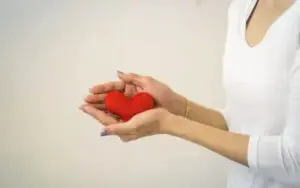 hands holding heart pillow