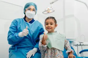 https://www.pexels.com/photo/dentist-and-her-patient-posing-at-the-camera-12917374/ Dental hygienist with child giving a thumbs up.